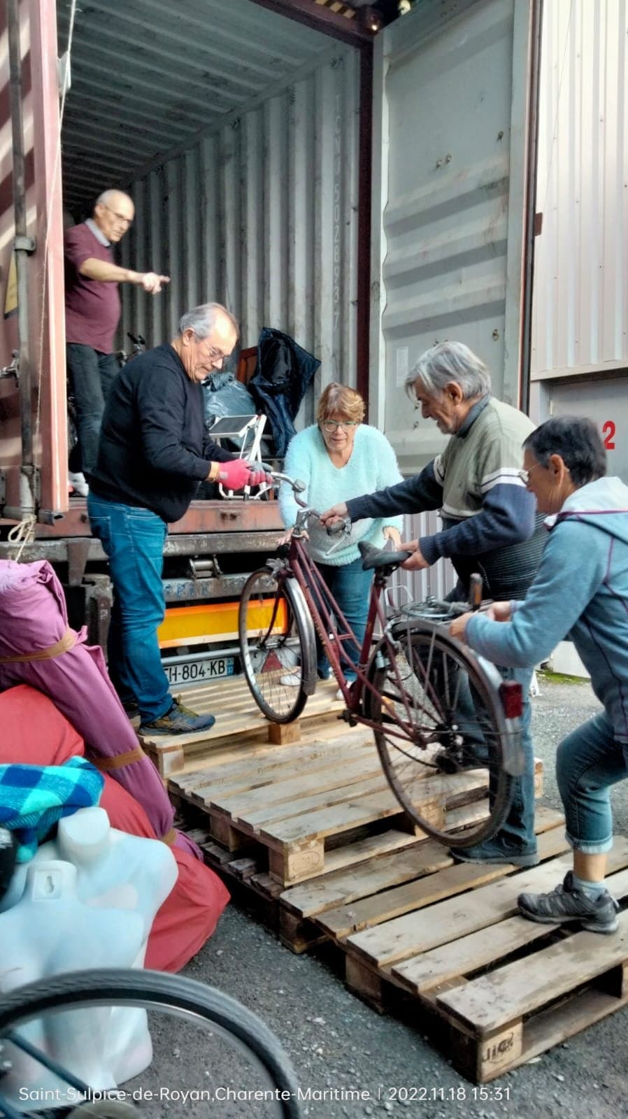Bénévoles hissant un vélo à l'intérieur du container.