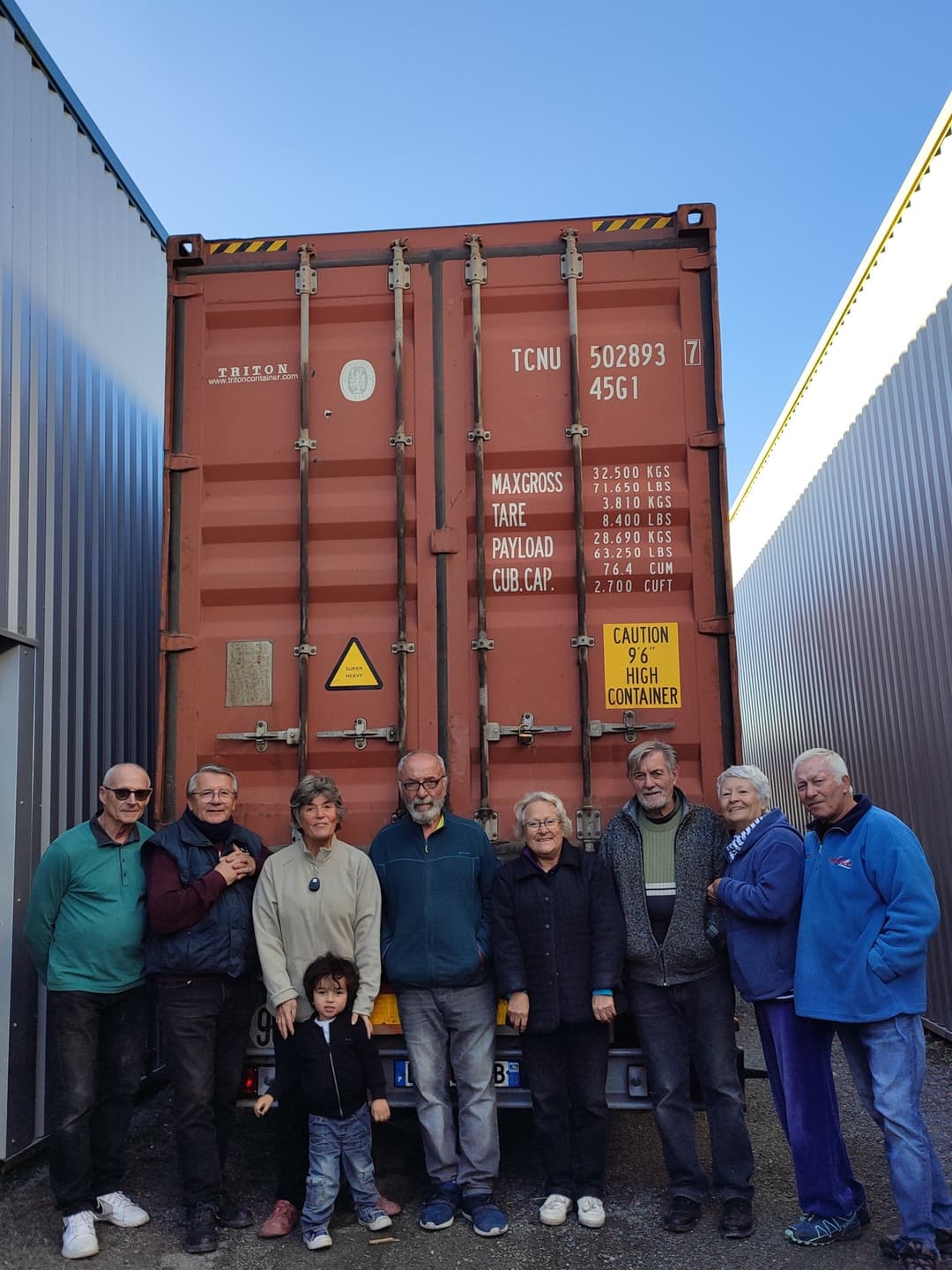 Groupe de bénévoles posant devant le container plombé, prêt à partir.