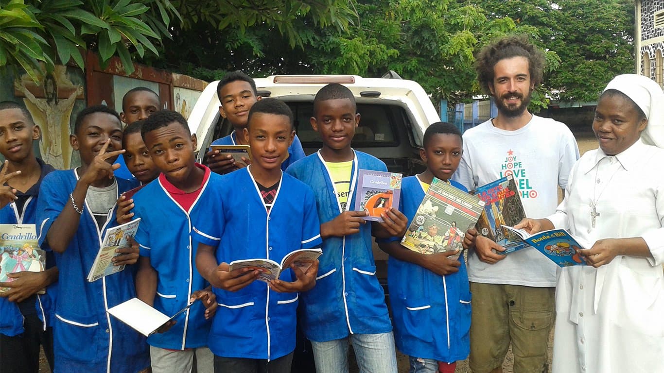 Groupe d'enfants en uniforme scolaire tenant les livres et fournitures reçus.