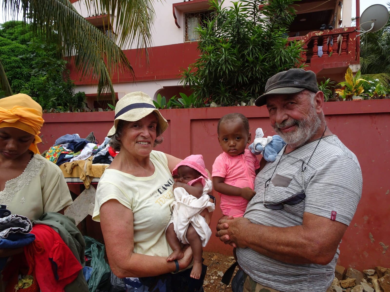 Bénévoles tenant un bébé dans les bras, entourés de vêtements à distribuer.