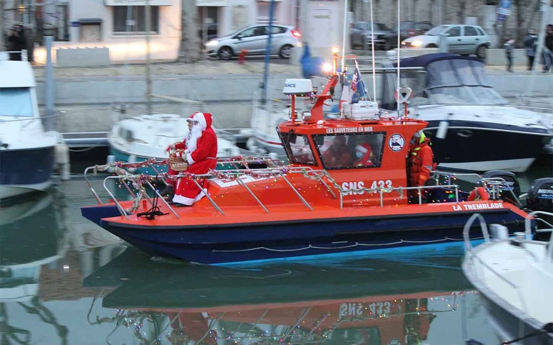 Père Noël arrivant à bord d'un canot de sauvetage dans le port, pour le marché de Noël.