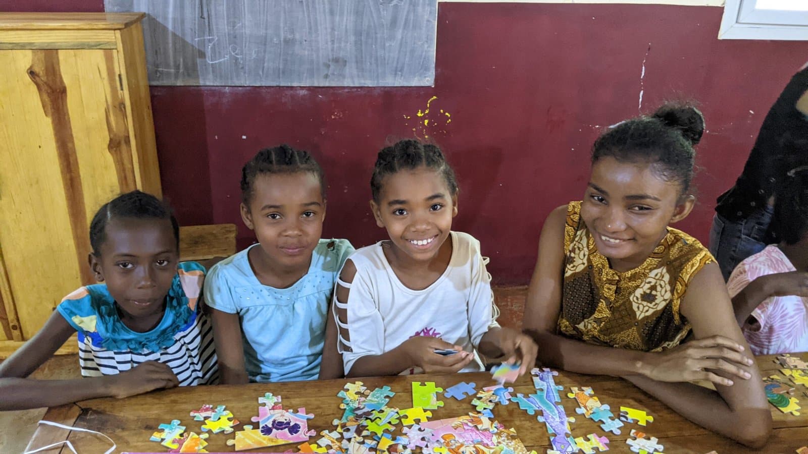 Deux fillettes souriantes faisant un puzzle avec une éducatrice.