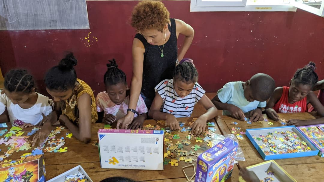 Bénévole aidant des enfants à assembler un puzzle.