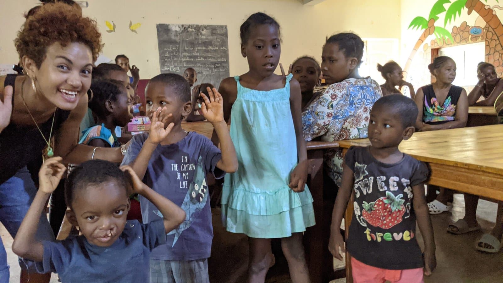 Enfants saluant dans une salle de classe.