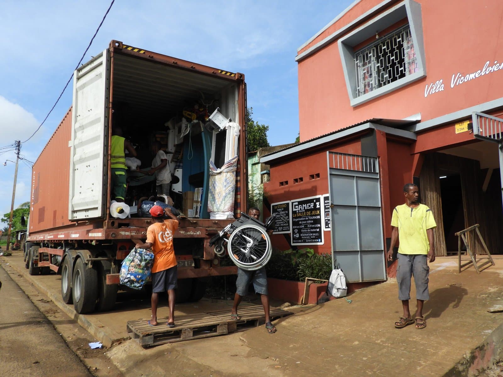 Déchargement du container à l'arrivée, meubles et cartons visibles à l'intérieur.