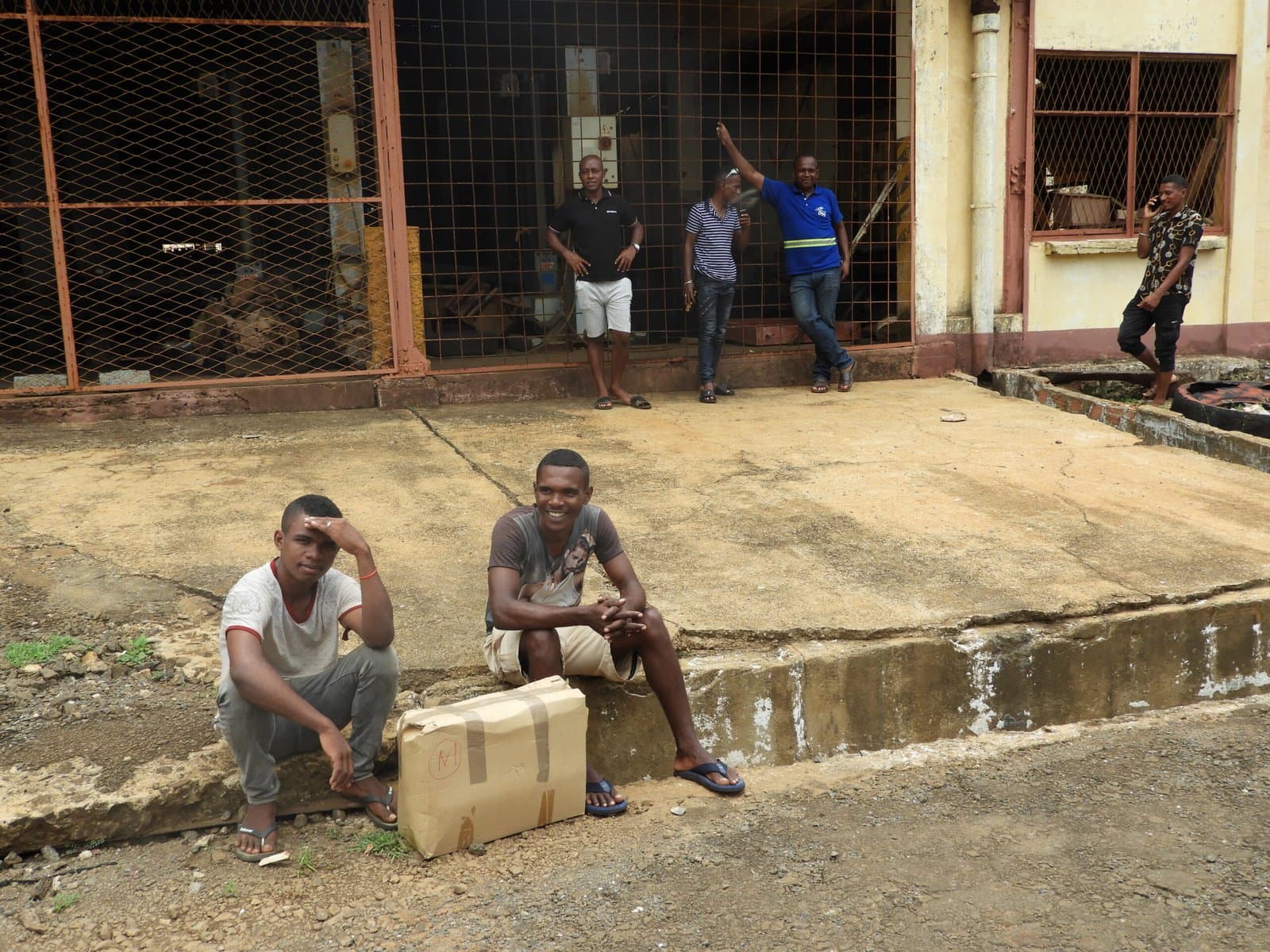 Deux jeunes hommes assis devant l'entrepôt de stockage.