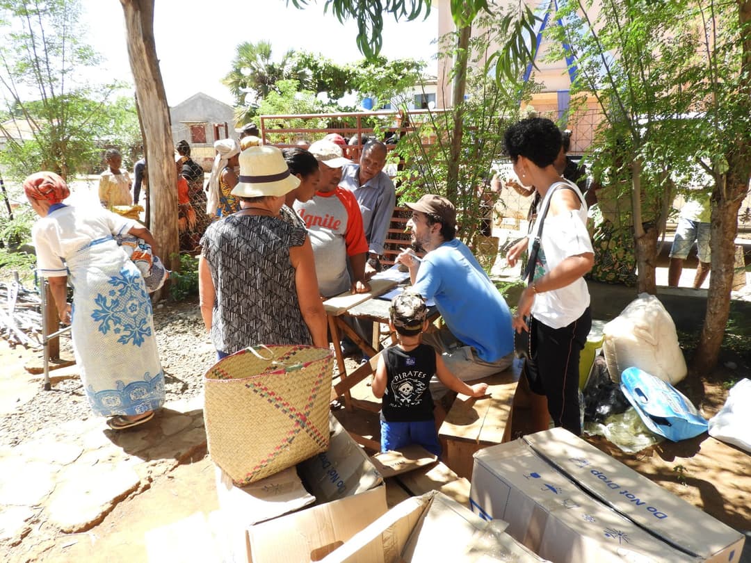 Bénévoles et habitants réunis autour d'une table et de paniers pendant la distribution.