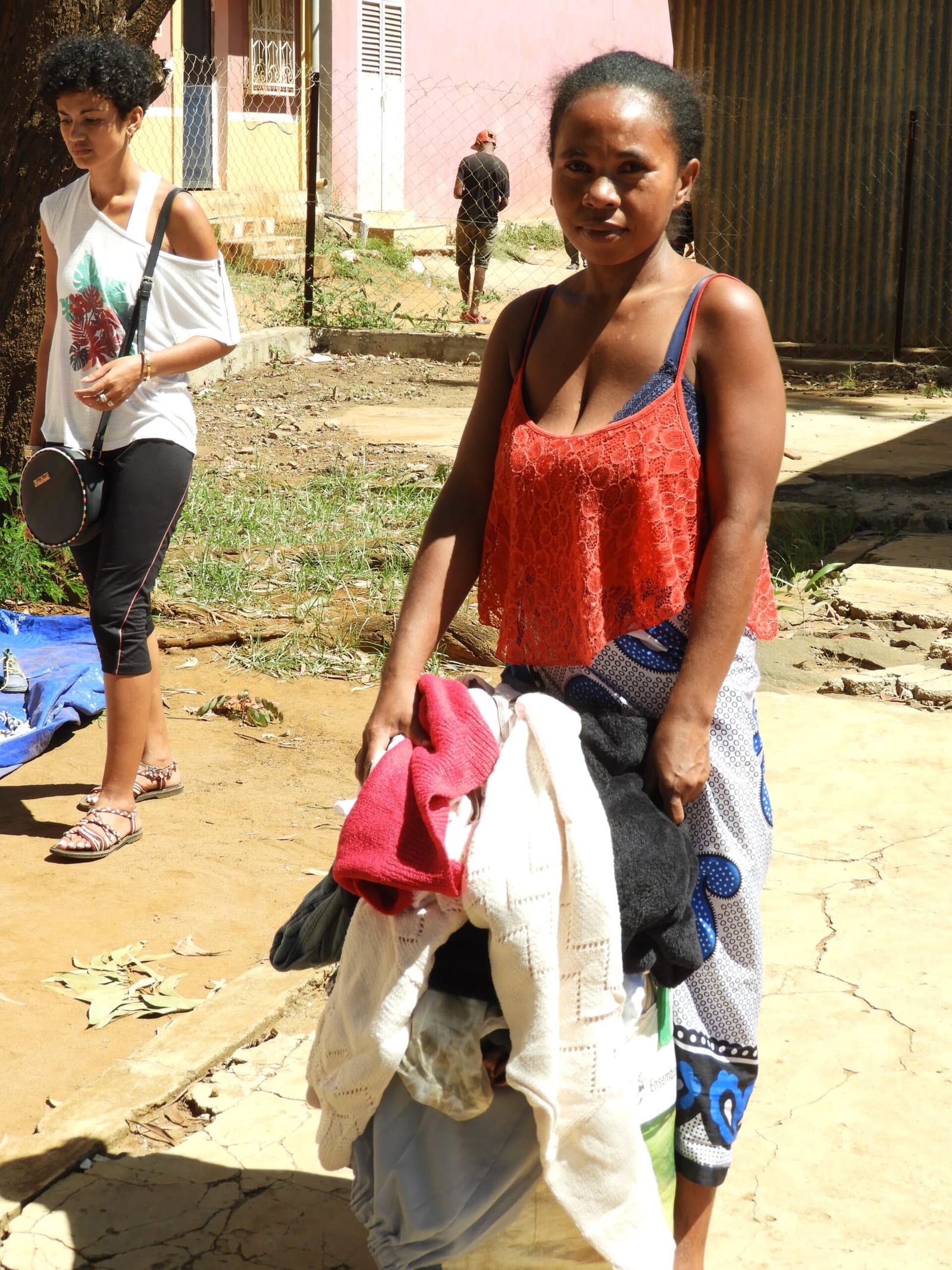 Femme debout en extérieur, tenant des vêtements.