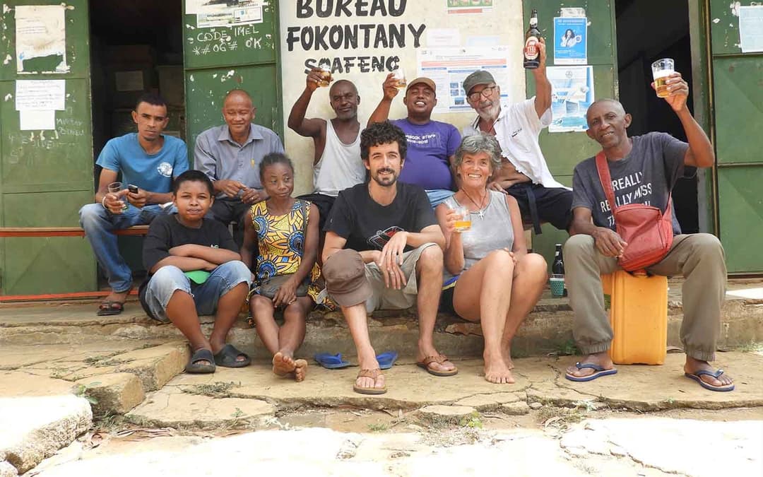 Bénévoles et un habitant du quartier posant ensemble devant le bureau du Fokontany Soafeno.