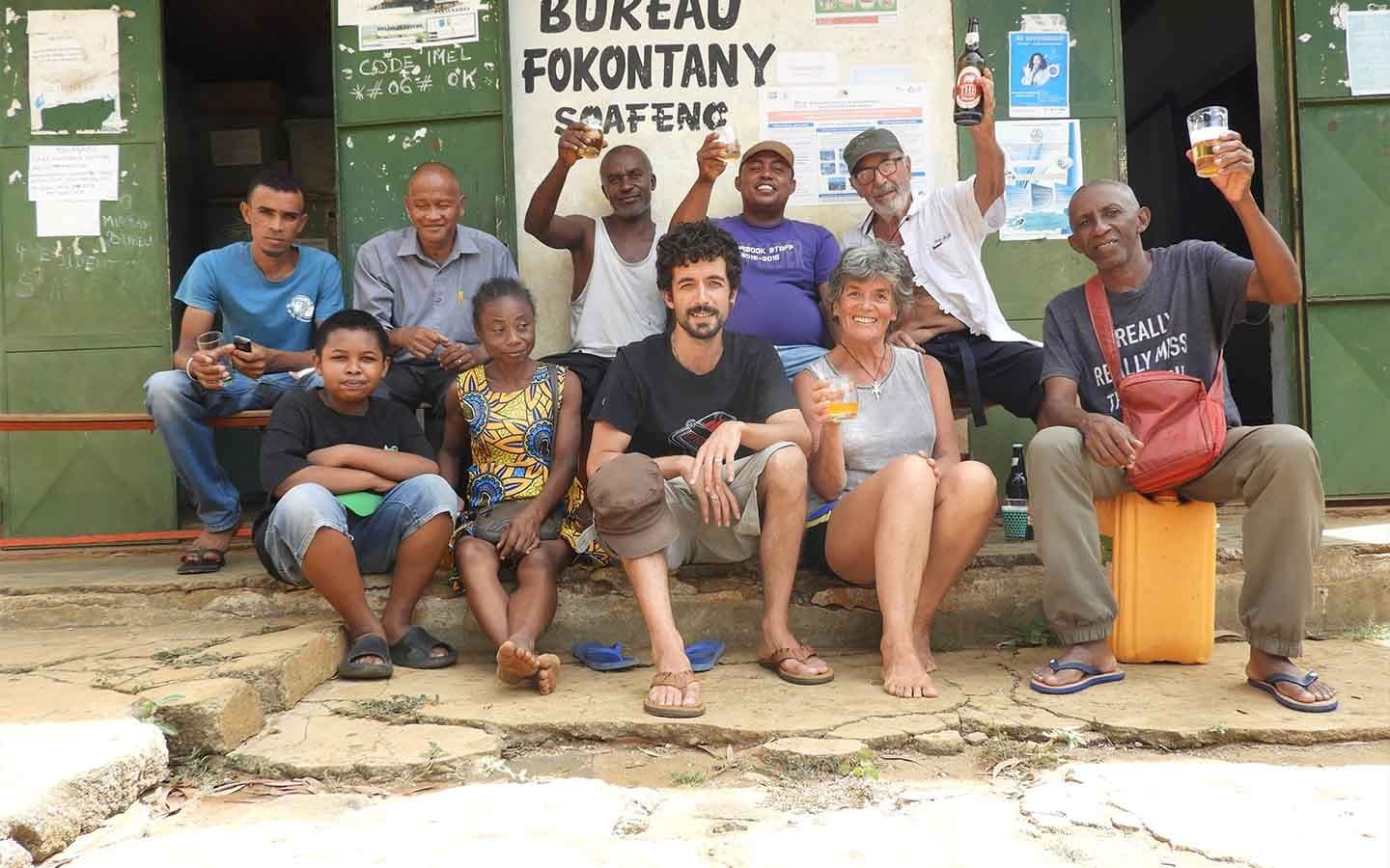 Bénévoles et un habitant du quartier posant ensemble devant le bureau du Fokontany Soafeno.